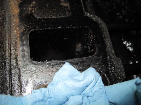 1989 Ford Bronco - A blue cloth is used to clean a section of a dark, greasy engine component.