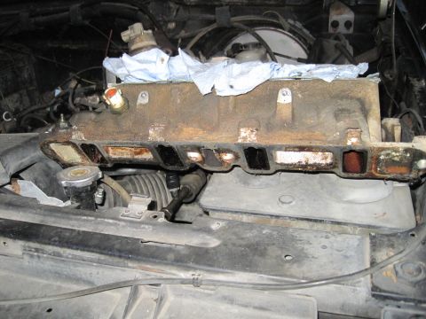 1989 Ford Bronco - Close-up of a rusty engine intake manifold during reassembly.