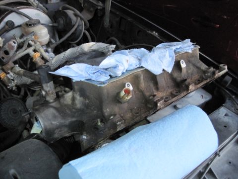 1989 Ford Bronco - Close-up of an engine intake manifold, partially covered with blue shop towels, with a roll of paper towels nearby.