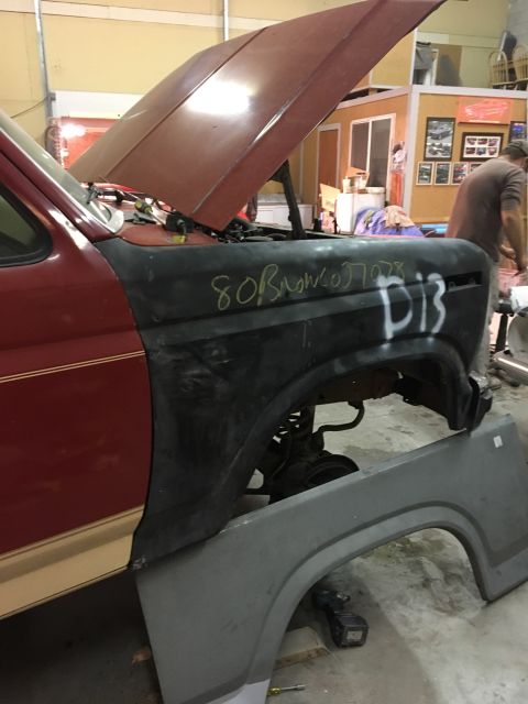 1985 Ford Bronco - A red Ford Bronco with its hood up, showing a fender with handwritten markings indicating it's from 1980.