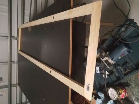 1994 Ford Bronco - A wooden frame, labeled "Left Side", sits on a dark surface near tools and a saw.