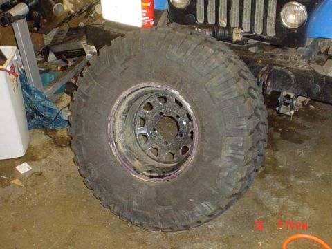 1983 Ford Bronco - A large off-road tire and wheel assembly is shown, with part of a vehicle visible in the background.