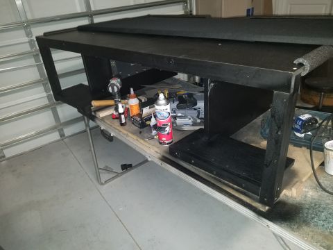 1994 Ford Bronco - A black stereo cabinet sits on a folding table with various tools and spray cans around it in a garage setting.
