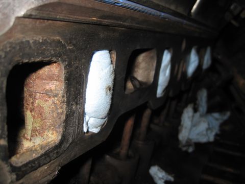 1989 Ford Bronco - Close-up view of an engine's intake manifold, showing ports covered with rags to prevent debris entry.