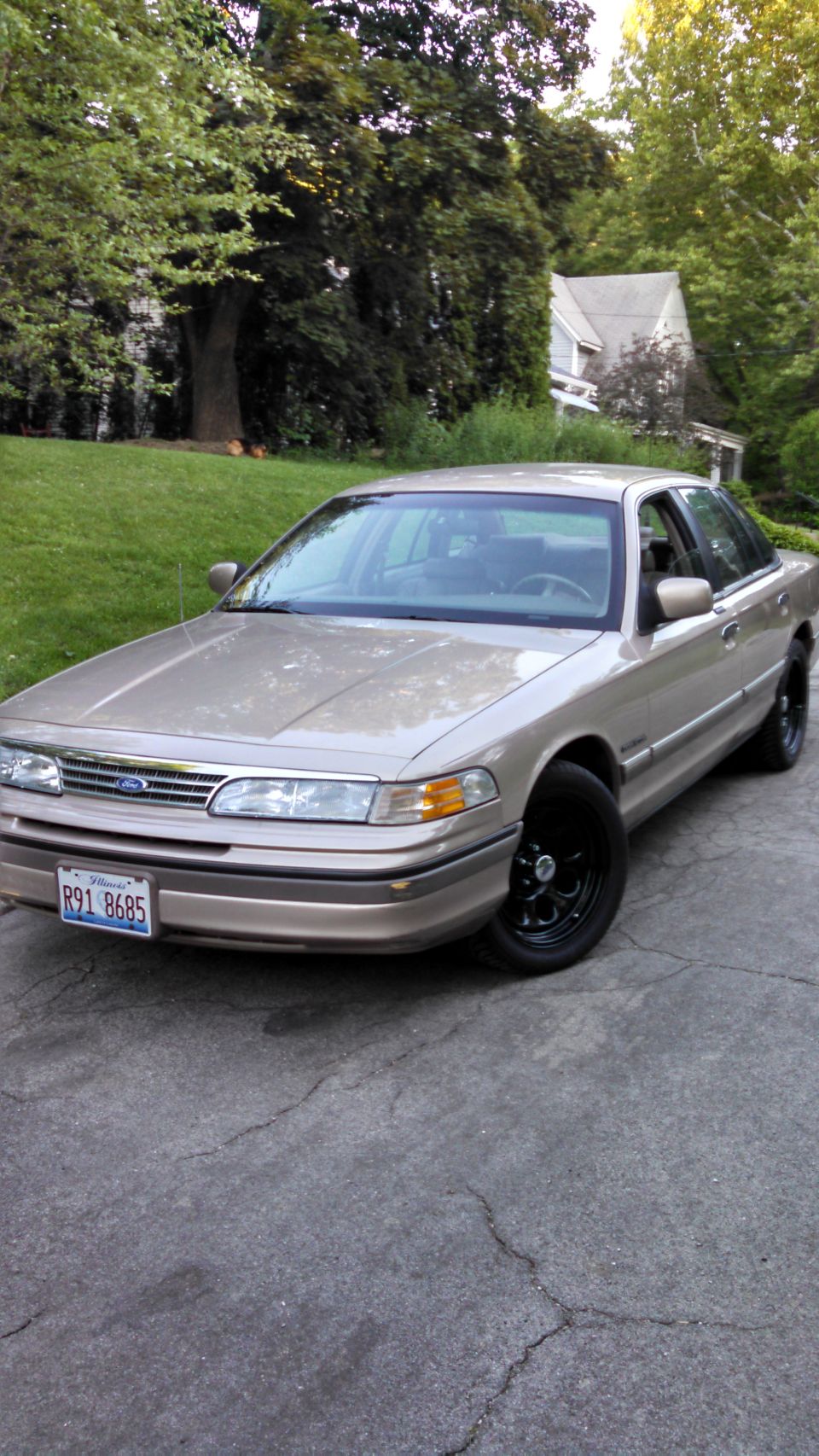 Tan 1995 Ford Crown Victoria with black wheels parked on a driveway