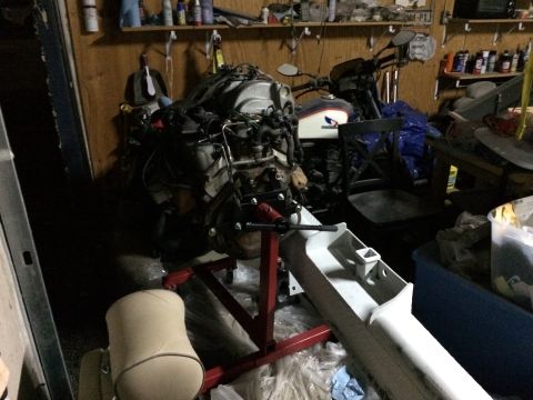 1989 Ford Bronco - Engine on a stand in a garage, with a motorcycle partially visible behind it. No year is discernible from the image.
