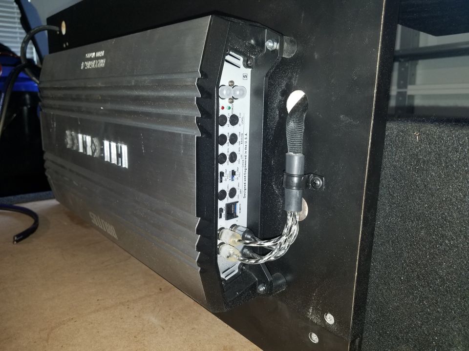 car amplifier mounted on a black panel, wires connected