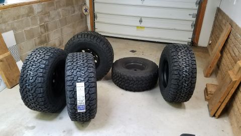 1994 Ford Bronco - Several off-road tires are displayed on the concrete floor of a garage, ready for installation.