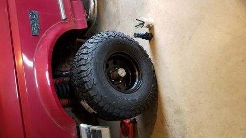 1994 Ford Bronco - A red Ford Bronco is shown with a spare tire mounted on its rear quarter panel.