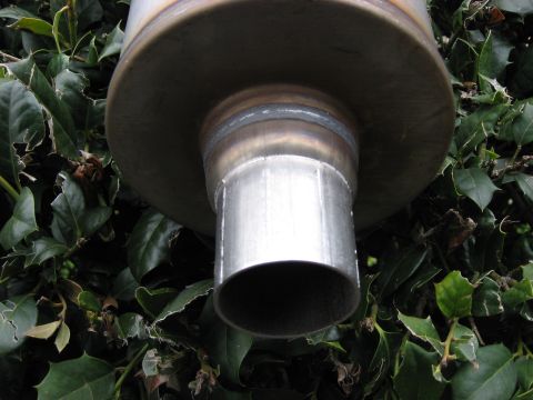 1987 Jaguar XJ6 - Close-up view of a vehicle's exhaust pipe, showing metalwork and surrounding foliage.