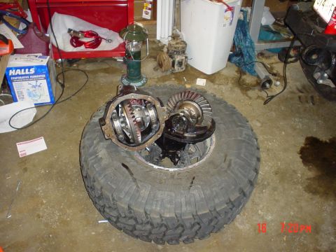 1983 Ford Bronco - Differential gears and ring gear are displayed on a tire in a garage setting.