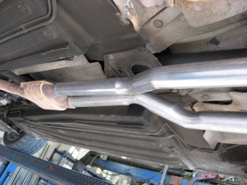 1987 Jaguar XJ6 - The underside of a vehicle shows a newly installed dual exhaust system, including a catalytic converter.