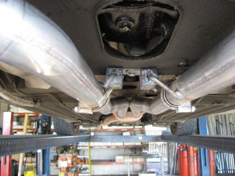 1987 Jaguar XJ6 - The underside of a vehicle shows a dual exhaust system with custom piping and hangers, lifted on a service rack.