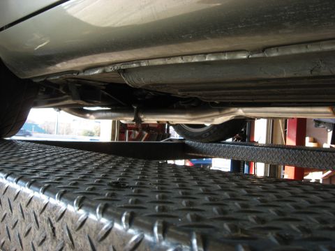 1987 Jaguar XJ6 - Underside view of a vehicle's exhaust system, showing pipes and muffler, elevated on a service lift.