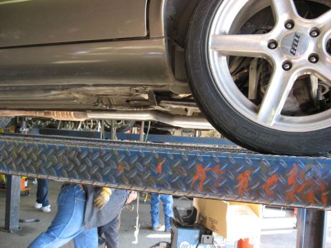 1987 Jaguar XJ6 - Car exhaust system and wheel visible while the vehicle is on a lift for service.