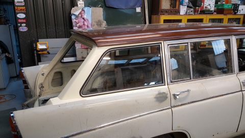 1962 MG B - This vehicle appears to be a station wagon, possibly undergoing restoration, with distinctive wood-grain trim on its roof.