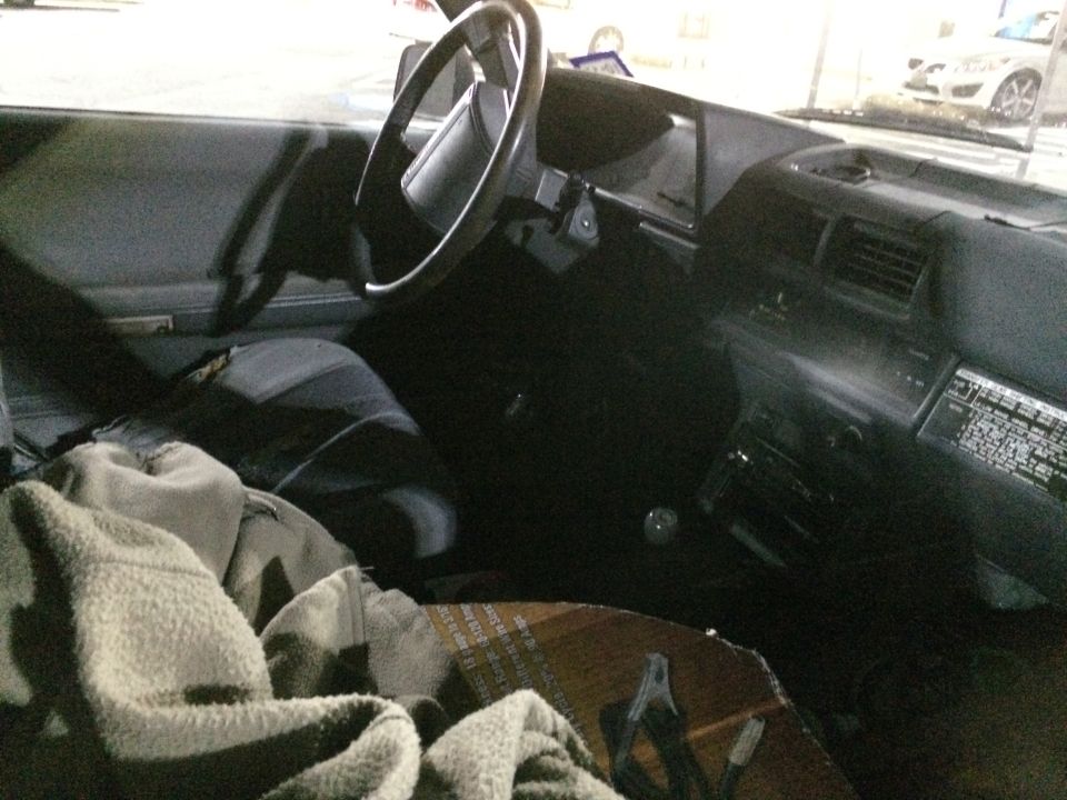 Car interior with gray seats, dashboard, and steering wheel. A blanket covers the passenger seat