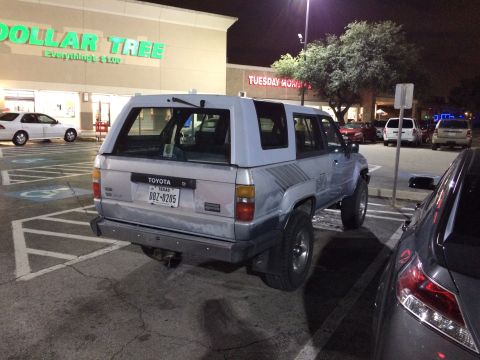 1985 Jaguar XJ6 - Toyota 4Runner with camper shell parked in a shopping center lot at night.