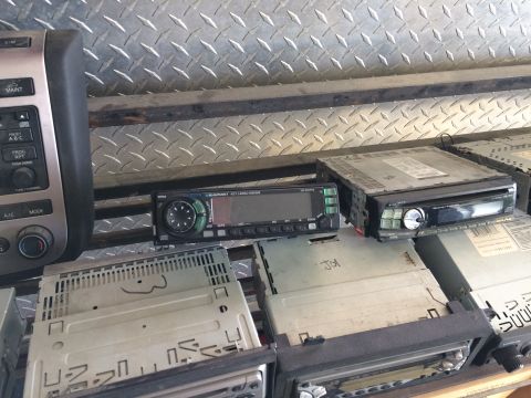 1985 Jaguar XJ6 - A collection of car stereos, some with visible labels and controls, are piled up.