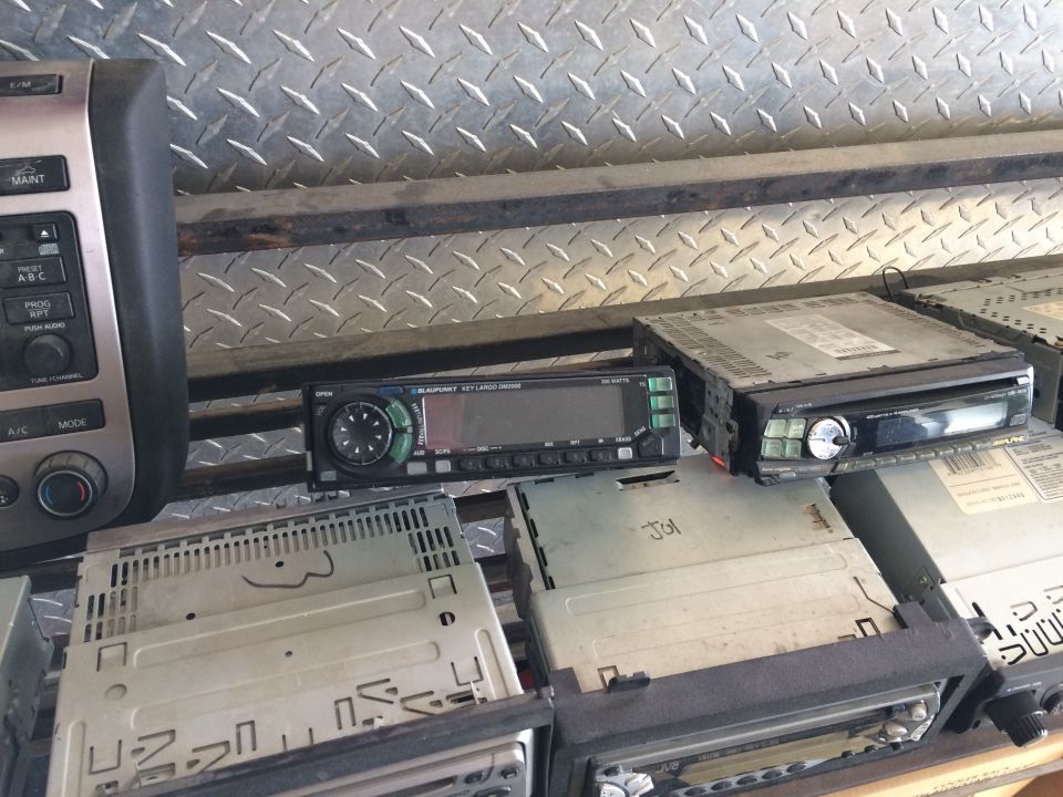 Several car stereos stacked on a shelf, including a Blaupunkt unit