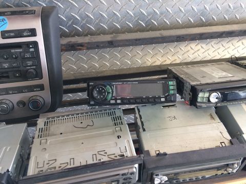 1985 Jaguar XJ6 - A collection of used car stereos and a climate control unit are displayed for sale or salvage.