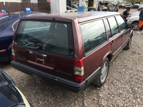 1985 Jaguar XJ6 - Maroon Volvo 240 wagon seen from the rear, parked next to another vehicle.