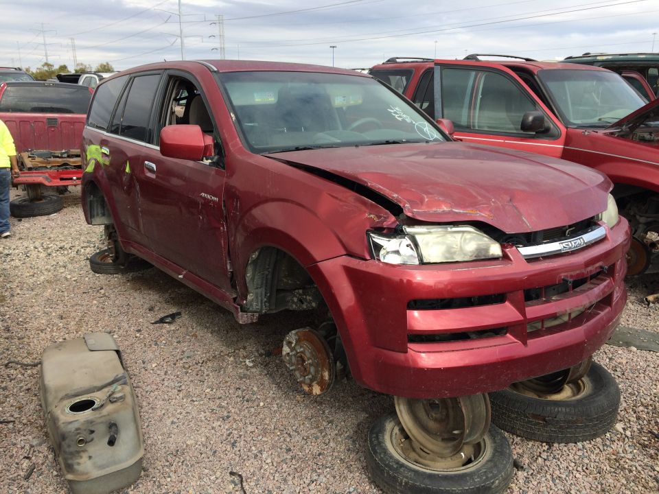 Red SUV missing wheels, front end damaged. Another red SUV is parked behind it