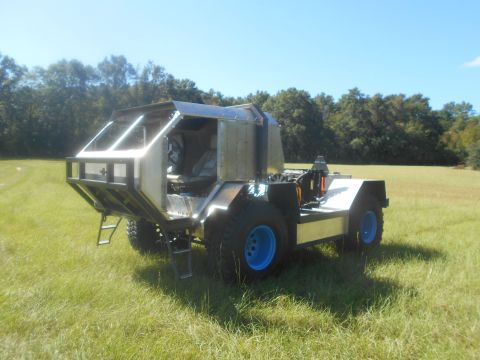 1992 Ford Bronco - A custom-built, unfinished vehicle with a metallic body and large, blue-rimmed tires sits in a grassy field under a clear blue sky. The veh…
