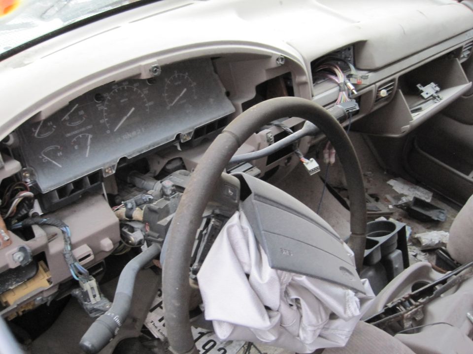 Interior of a car with deployed airbag, steering wheel, and dashboard.