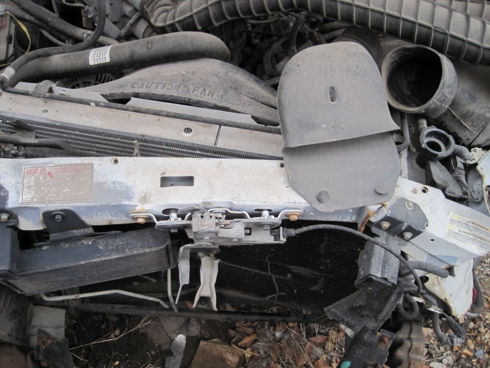 Close-up of a damaged car radiator, fan shroud, and engine components.