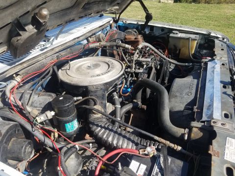 1984 Ford Bronco - The engine bay of a vehicle is shown with various components and wiring visible under the hood.