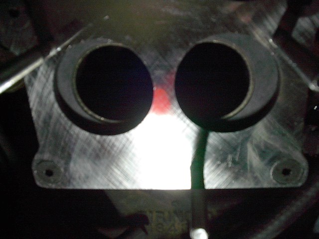 Engine intake manifold with two large circular openings and a red mark between them