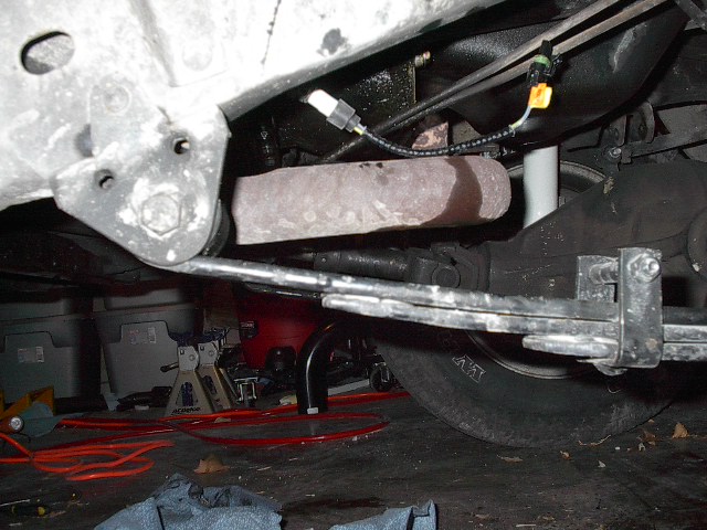 Underbody view showing leaf springs, driveshaft, and exhaust pipe. A sensor wire is visible near the exhaust