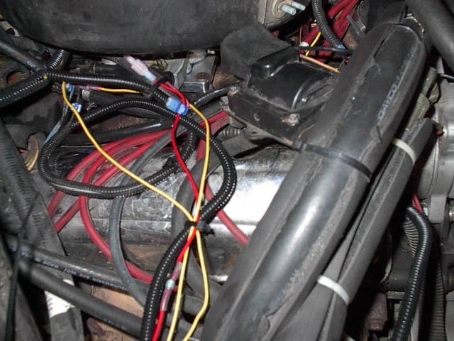 Close-up of a vehicle's engine wiring harness with red and yellow wires