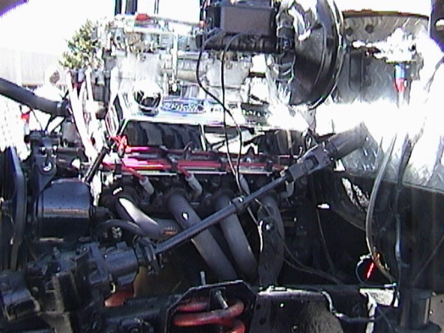 Engine with chrome intake manifold and red spark plug wires, viewed from the front