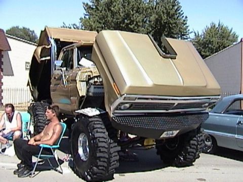 1995 Ford Bronco - Gold-painted full-size Ford built as a monster truck on a very tall lifted chassis with enormous mud tires and a diamond-plate front end, h…