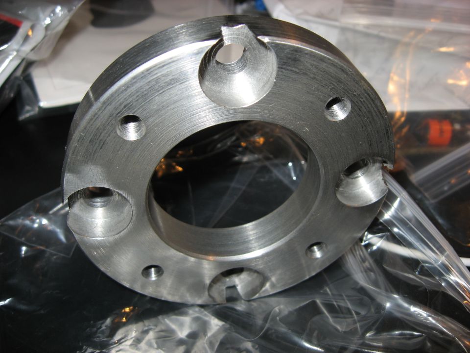 Machined metal part with six bolt holes and four angled recesses
