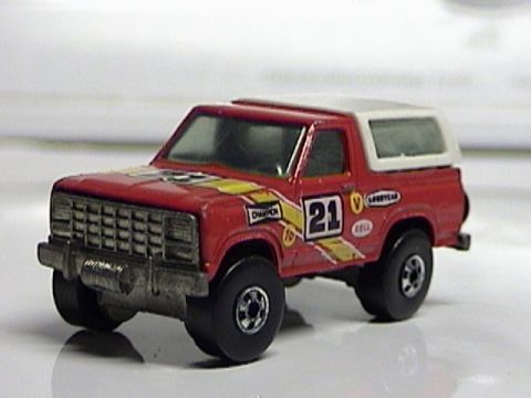1979 Ford Bronco - A close-up view of a red toy truck, detailed with racing decals and a white camper shell.