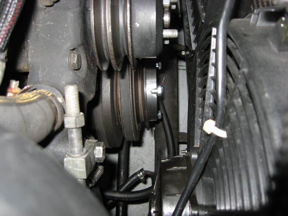 Close-up of engine pulleys and fan blades with hoses and mounting hardware