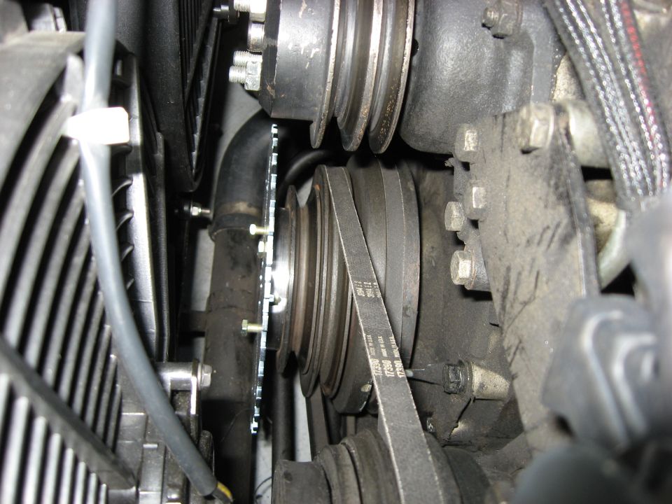 Close-up of serpentine belt, pulleys, and engine components in a vehicle.