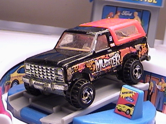 toy truck with 'MUDSTER' on side, on a blue ramp