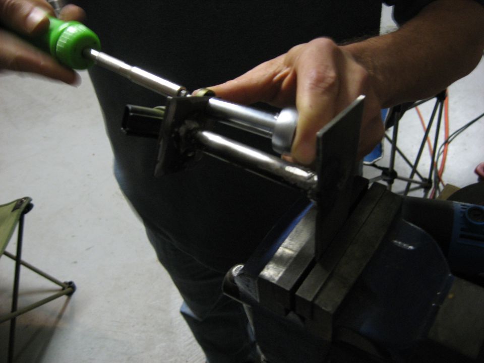 Person using a tool to adjust a metal apparatus clamped in a vise.