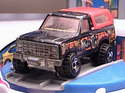 1979 Ford Bronco - This toy truck, likely a 1978 model, is black with an orange top and "Monster" graphics on its side.
