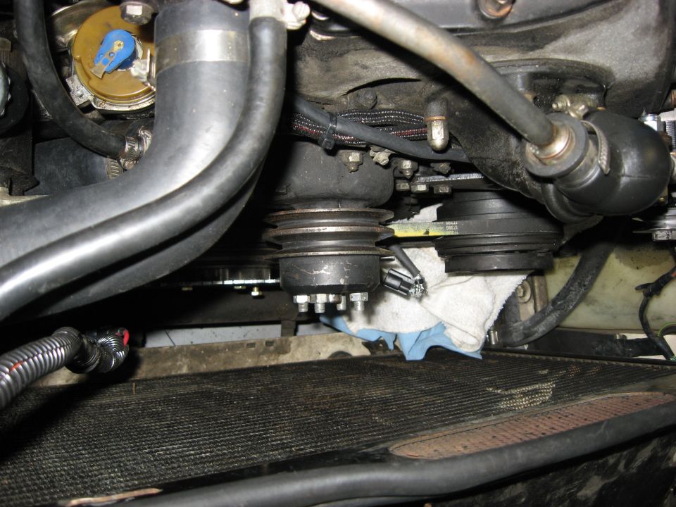 Vehicle engine bay showing serpentine belt, pulleys, and radiator.