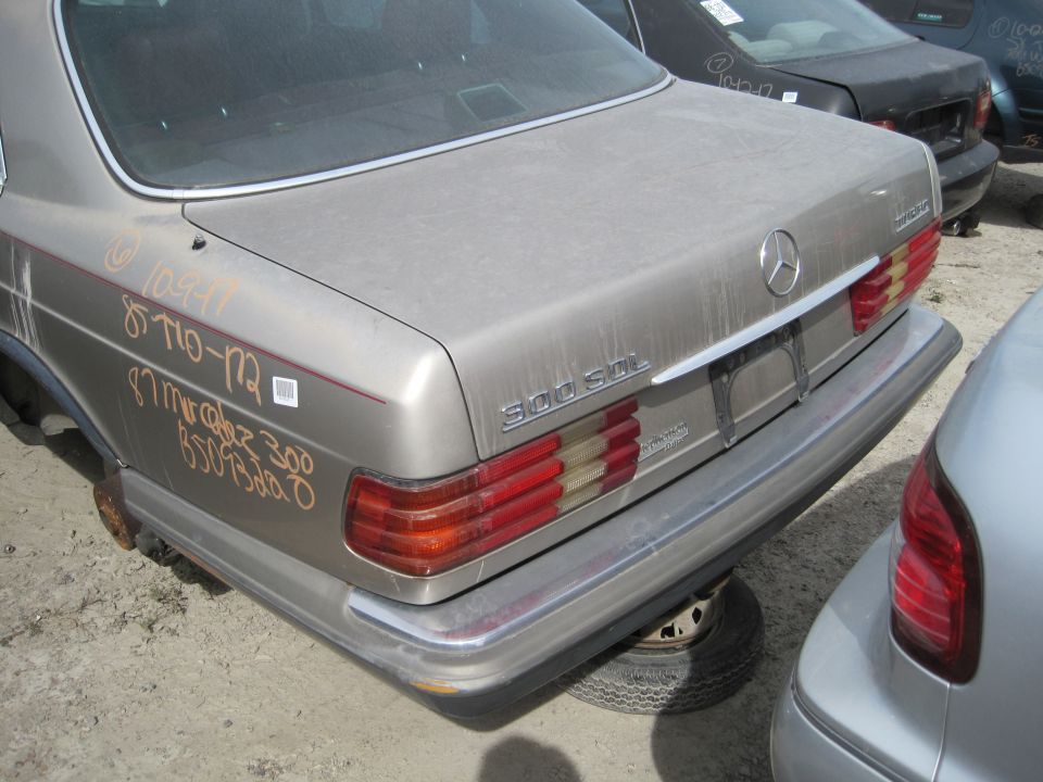 Rear quarter panel of a gold Mercedes-Benz sedan with handwritten text and barcode sticker.