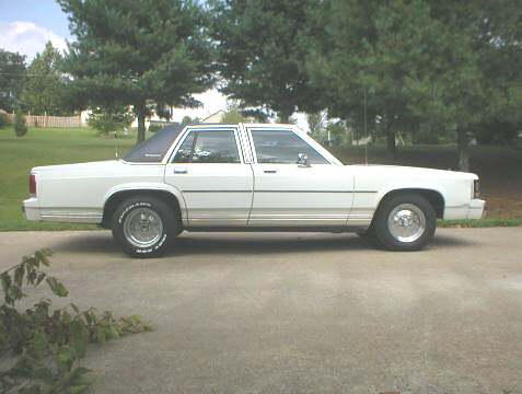 1989 Ford Crown Victoria - Side profile of a white 1989 Ford Crown Victoria sedan parked outdoors.