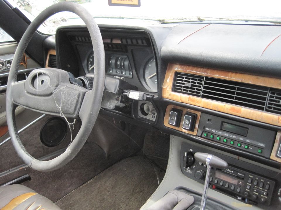 Interior view of a 1985 Jaguar XJ6 dashboard, steering wheel, and gear shifter.