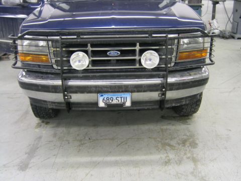 1994 Ford Bronco - Front view of a blue Ford truck with a protective grille guard and fog lights.