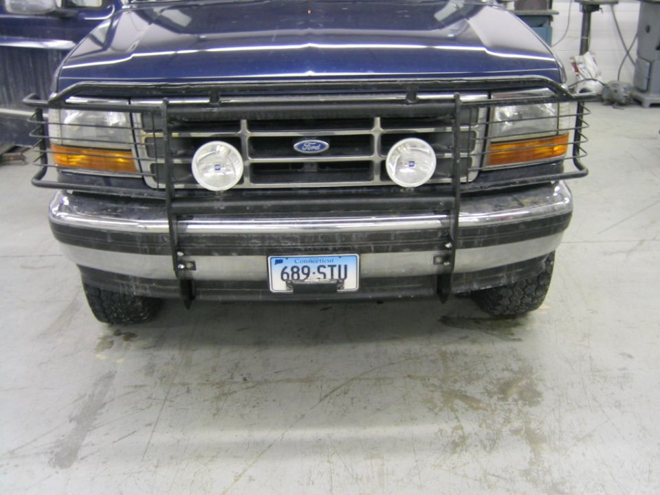 Front of dark blue Ford with black brush guard, twin driving lights and Connecticut plate