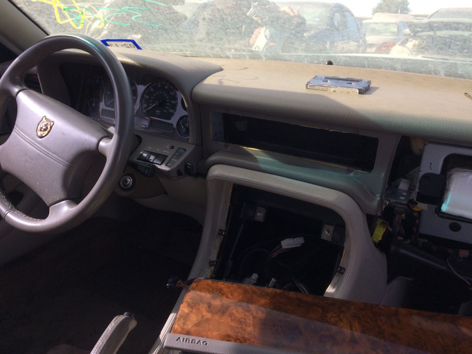Interior of a car dashboard with steering wheel, instrument cluster, and exposed wiring.